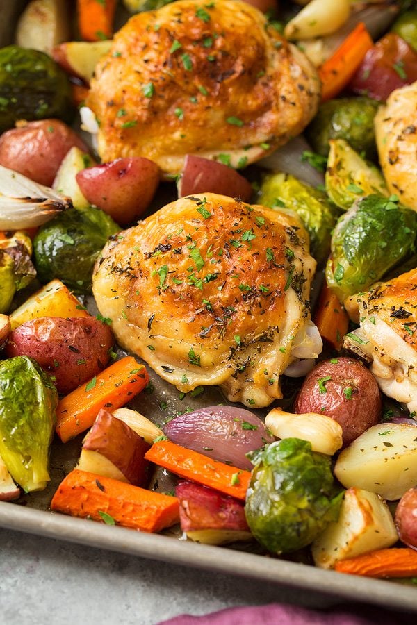 Close up image of baked chicken thigh with vegetables.