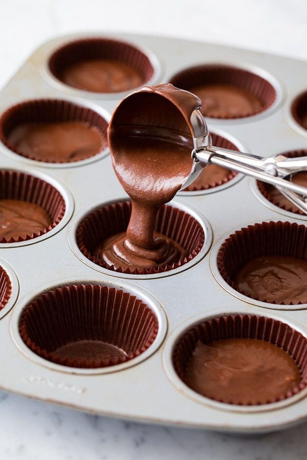 scooping chocolate cupcake batter into lined muffin tin