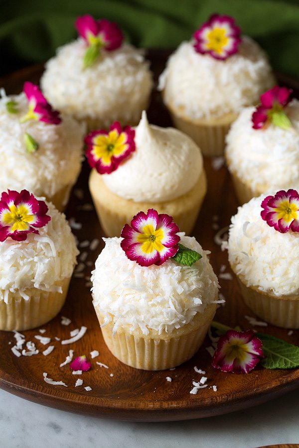 Coconut Cupcakes with coconut buttercream frosting on wood platter