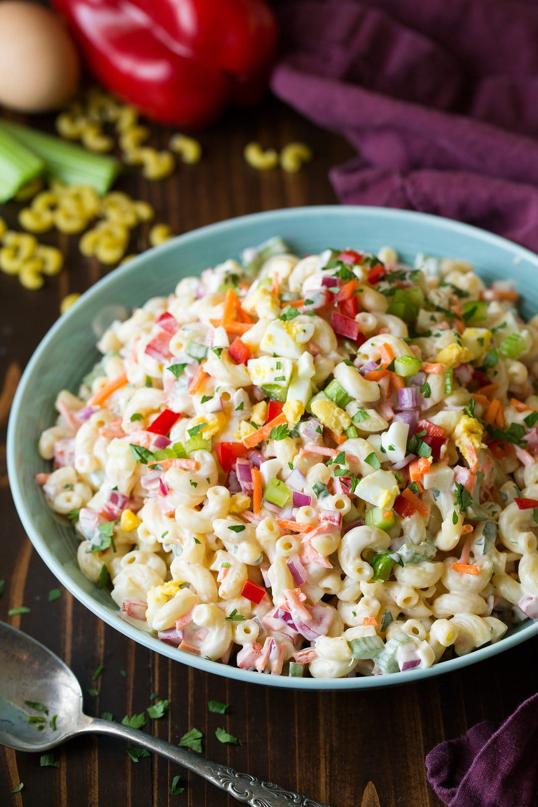 Serving dish of Macaroni Salad with red onion, celery, peppers, carrots and egg