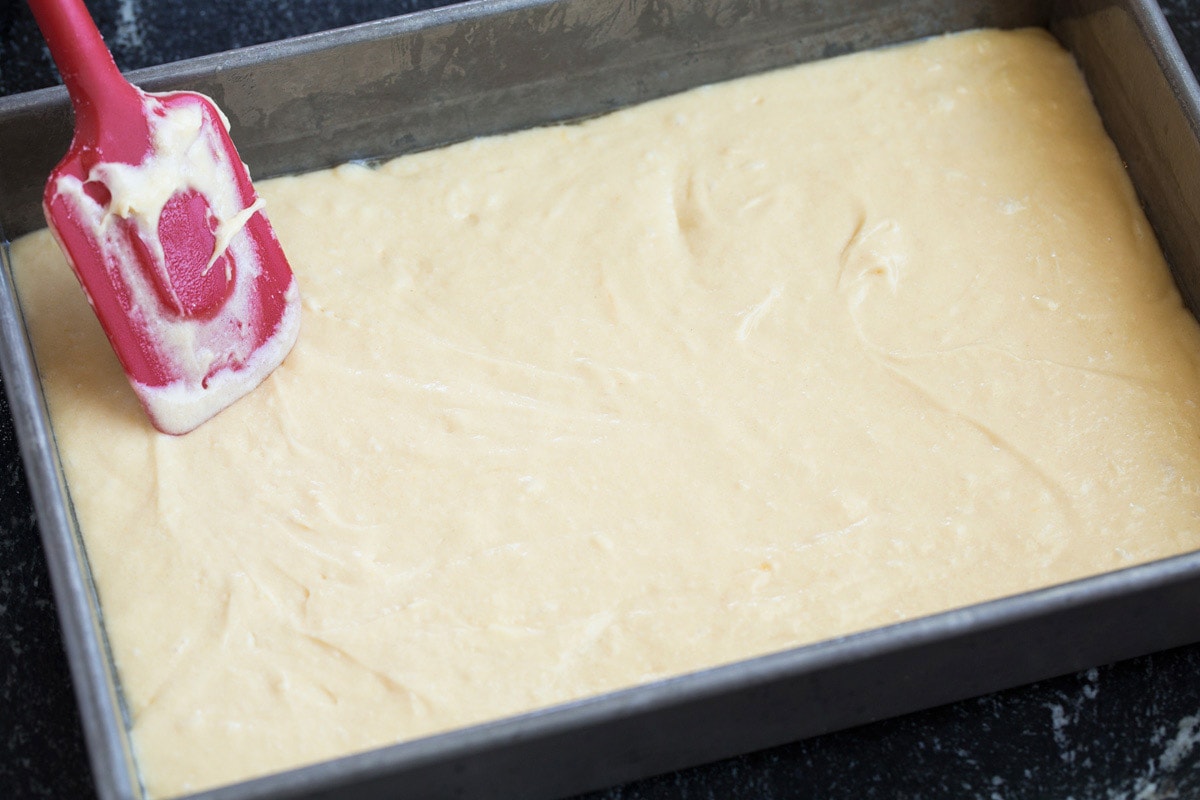Spreading tres leches cake batter in cake pan.