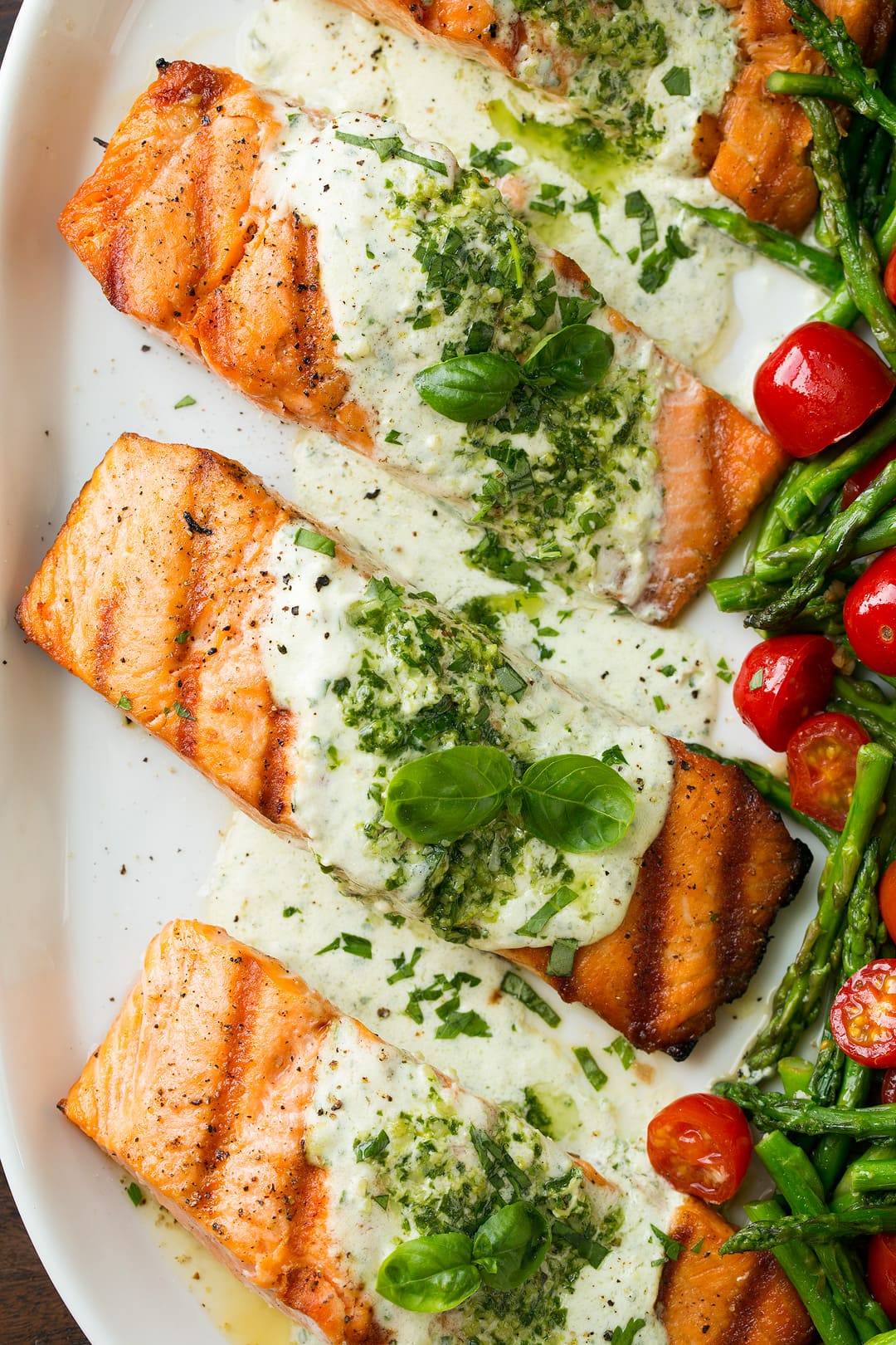 Grilled Salmon fillets with Creamy Pesto sauce on serving platter with veggies