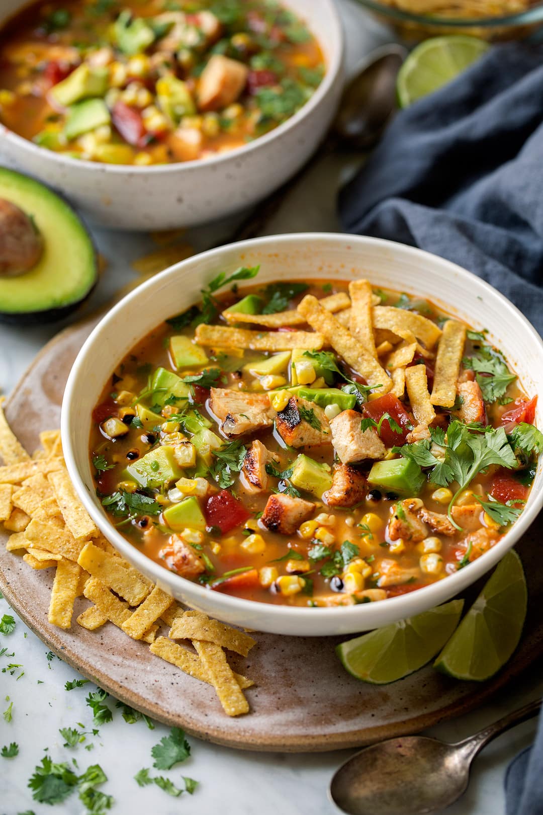Grilled Chicken Tortilla Soup in a white bowl with tortilla chips at the side