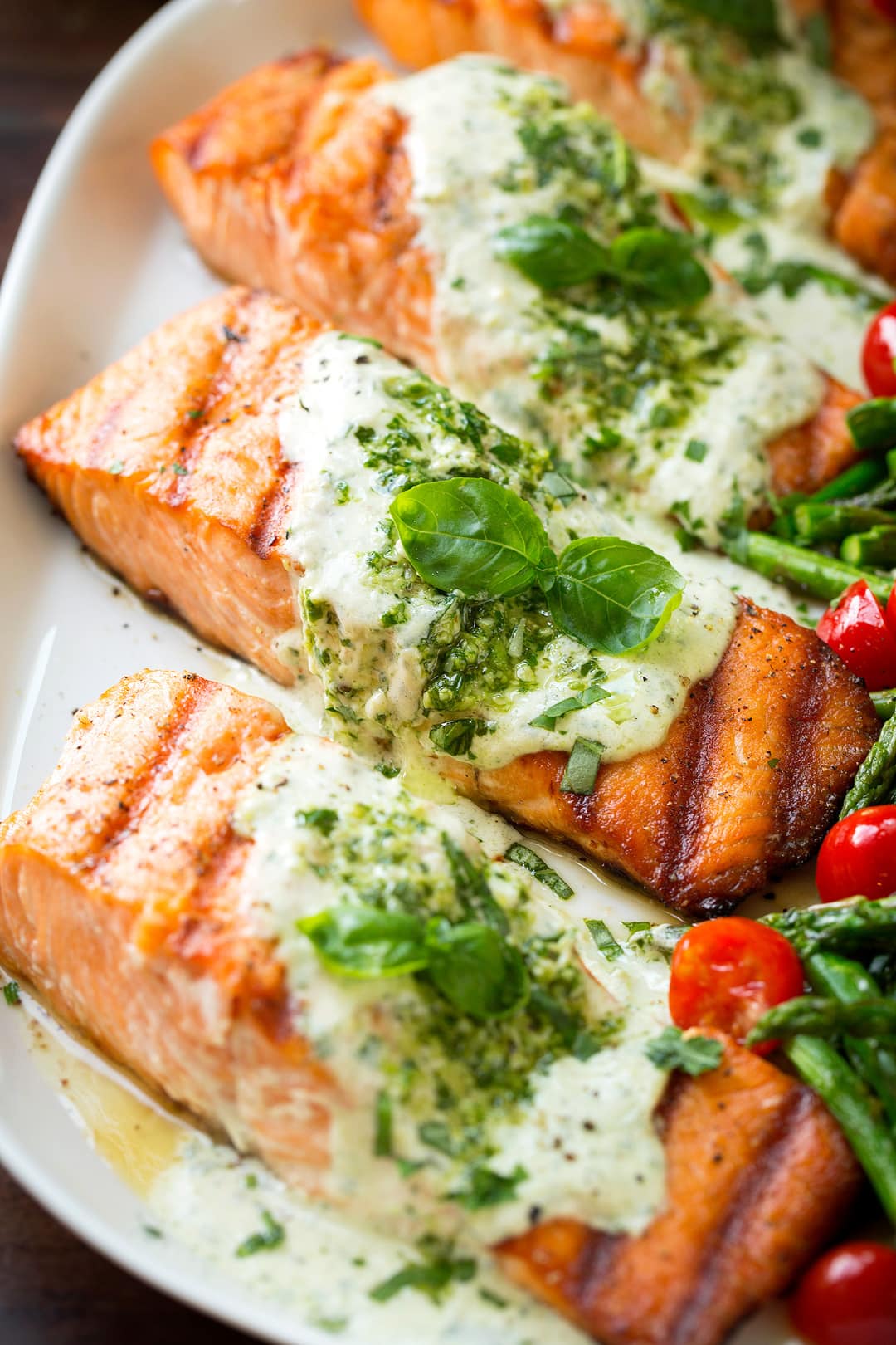 Grilled Salmon fillets with Pesto sauce on serving plate with veggies