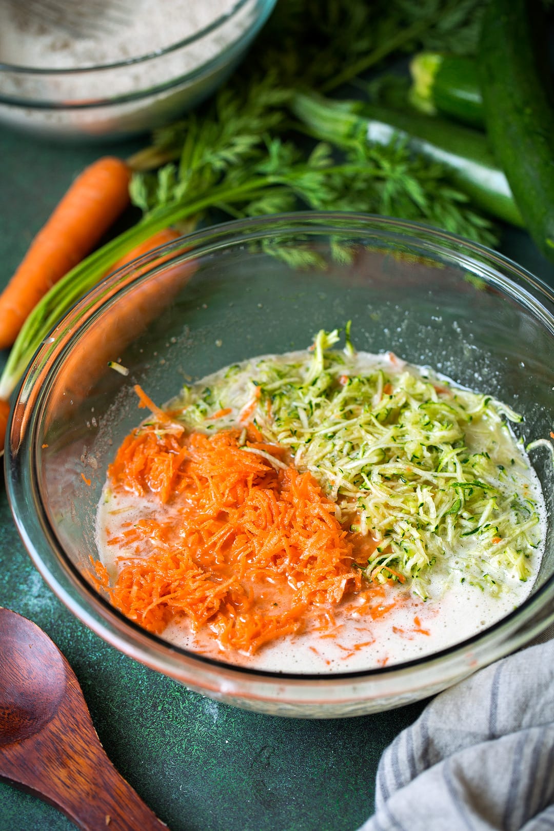 Muffins mixture with shredded zucchini and carrots in a mixing bowl.