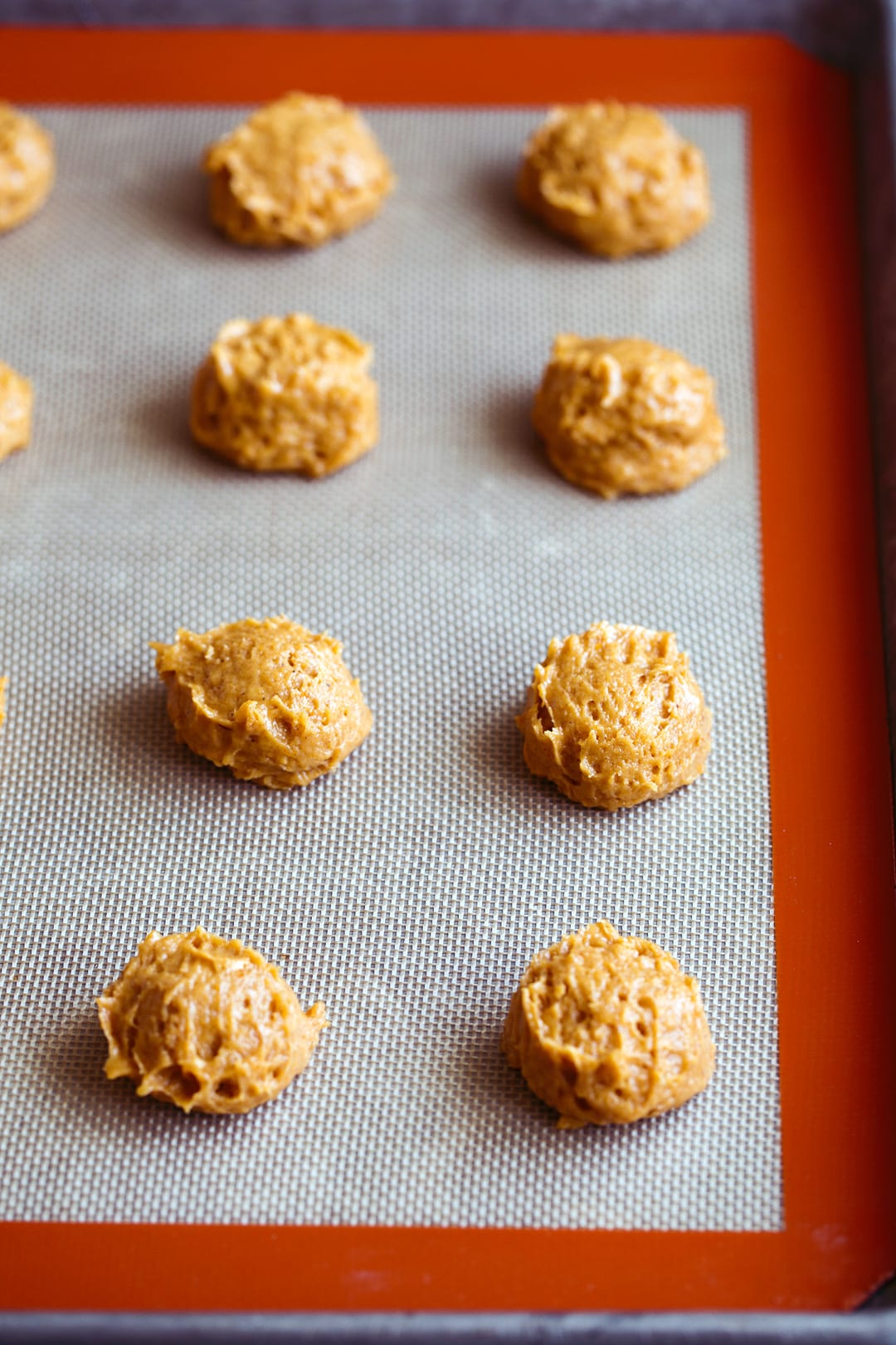 pumpkin cookie dough mounds on baking sheet before baking.