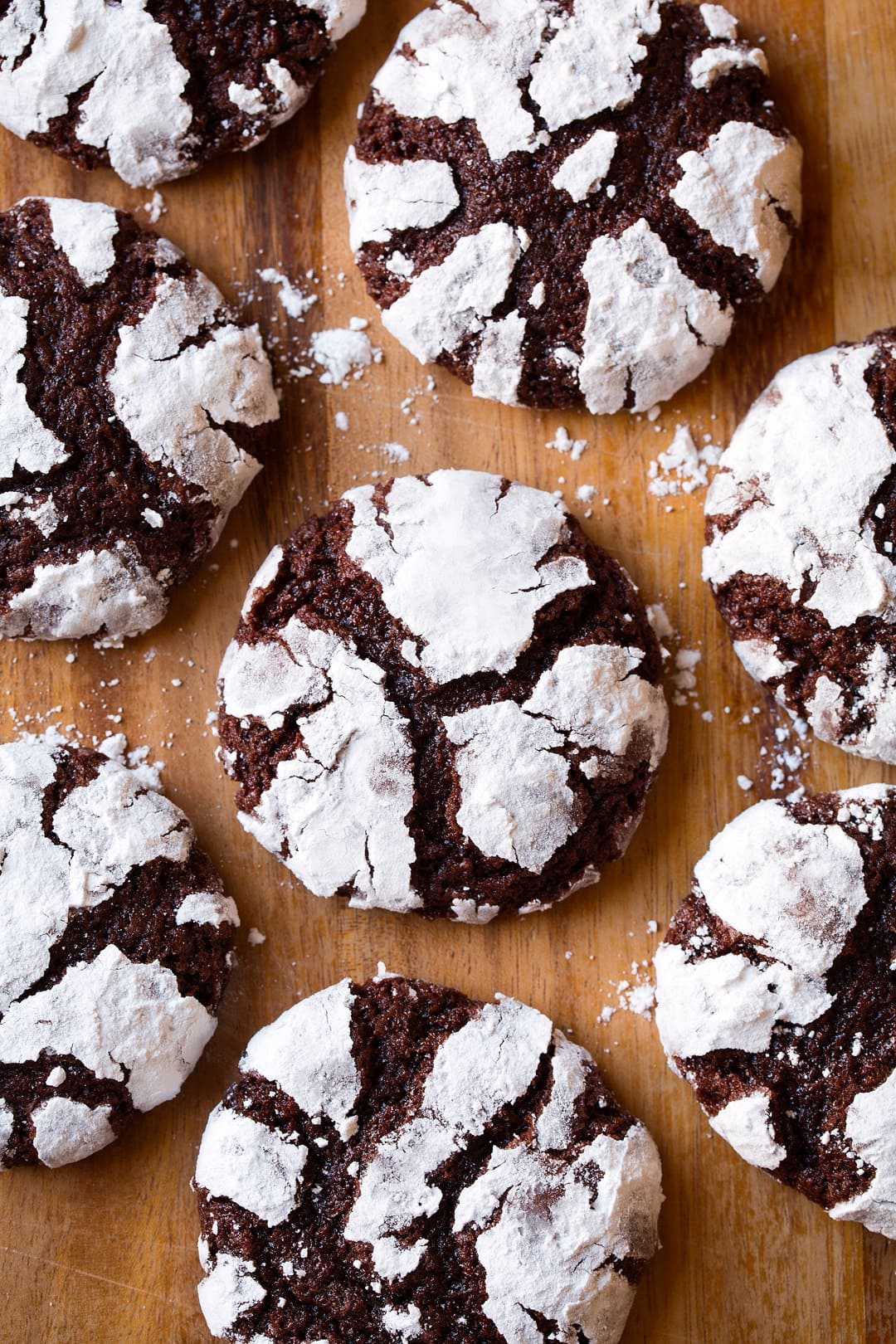 Chocolate Crinkle Cookies shown overhead laying on a wooden surface.