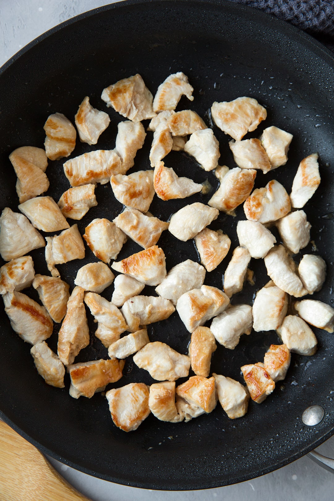 Chicken pieces browned in skillet for chicken broccoli stir fry