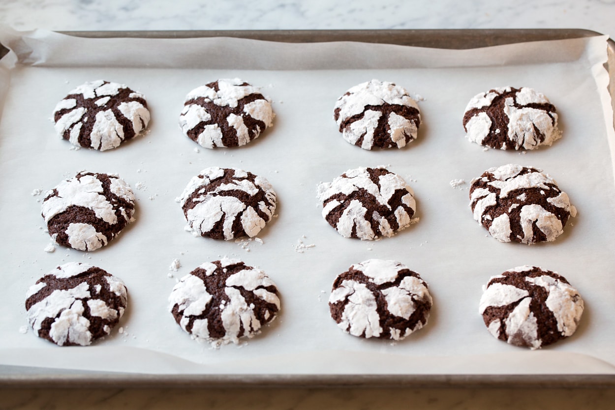 Chocolate Crinkle Cookies shown on parchment paper baking sheet after baking.