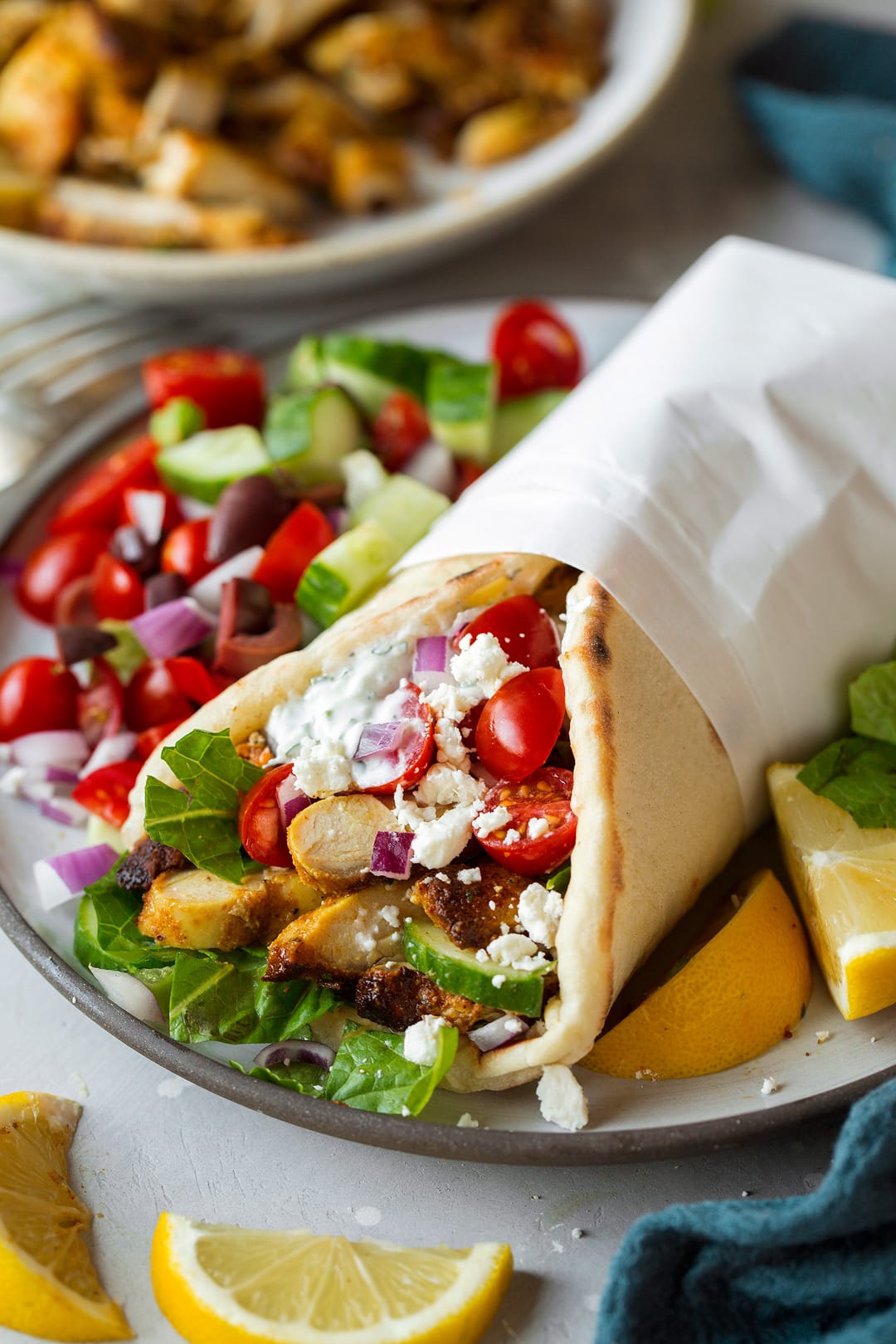 Chicken Shawarma shown here served in pita bread with a side of greek salad on a serving plate