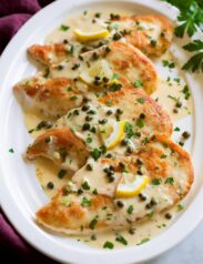 4 servings of chicken piccata on a white oval serving platter.