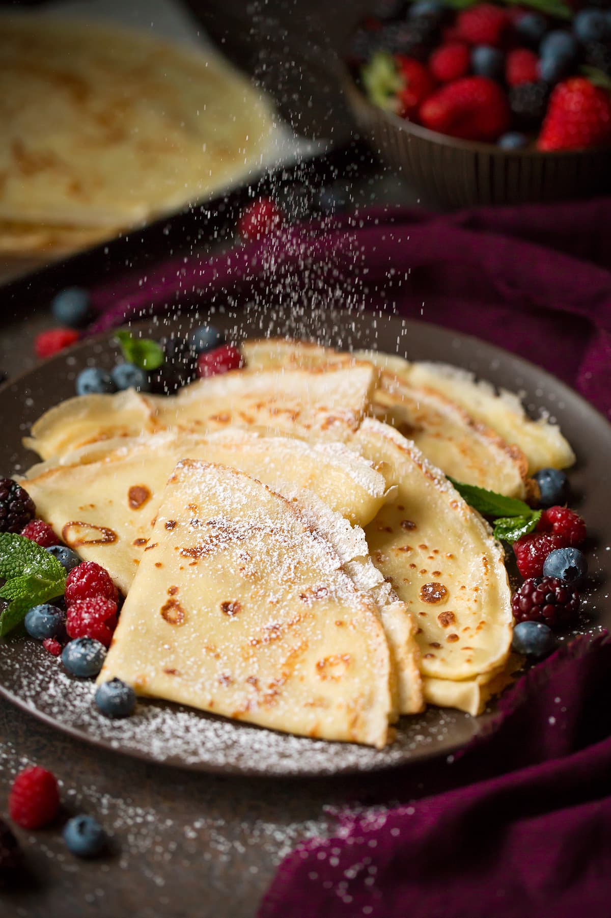 Dusting the best crepes, made from scratch with powdered sugar. 