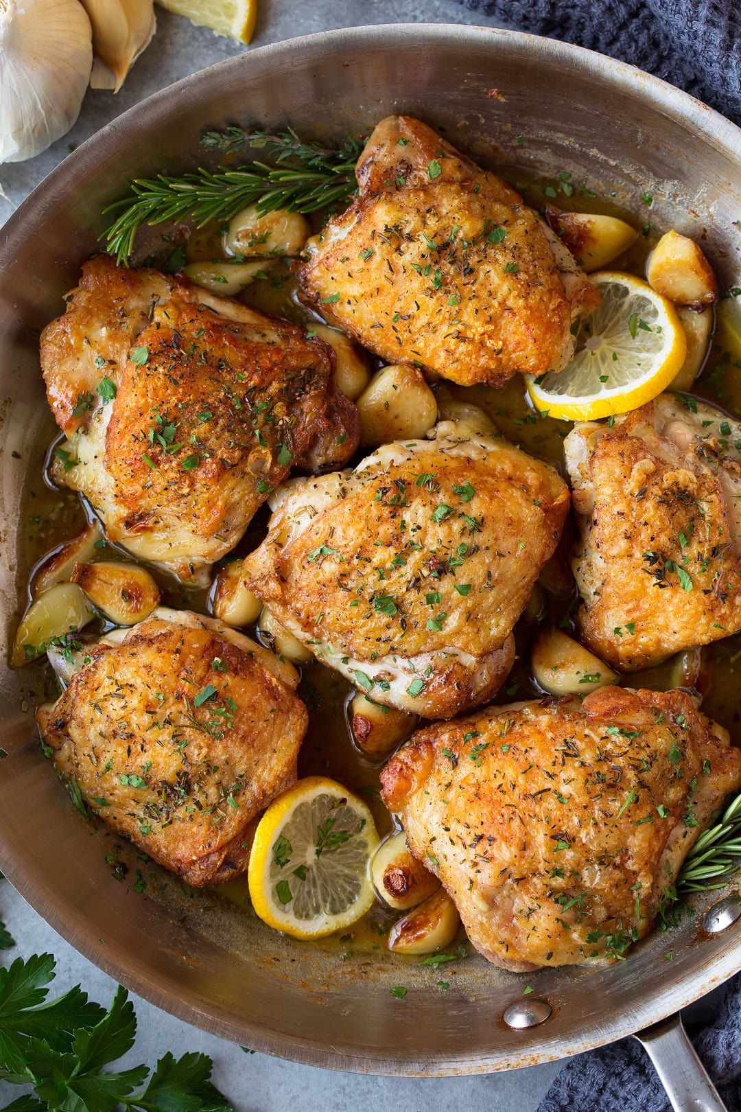 Roast chicken with garlic, lemons and herbs in a large stainless steel skillet after roasting.