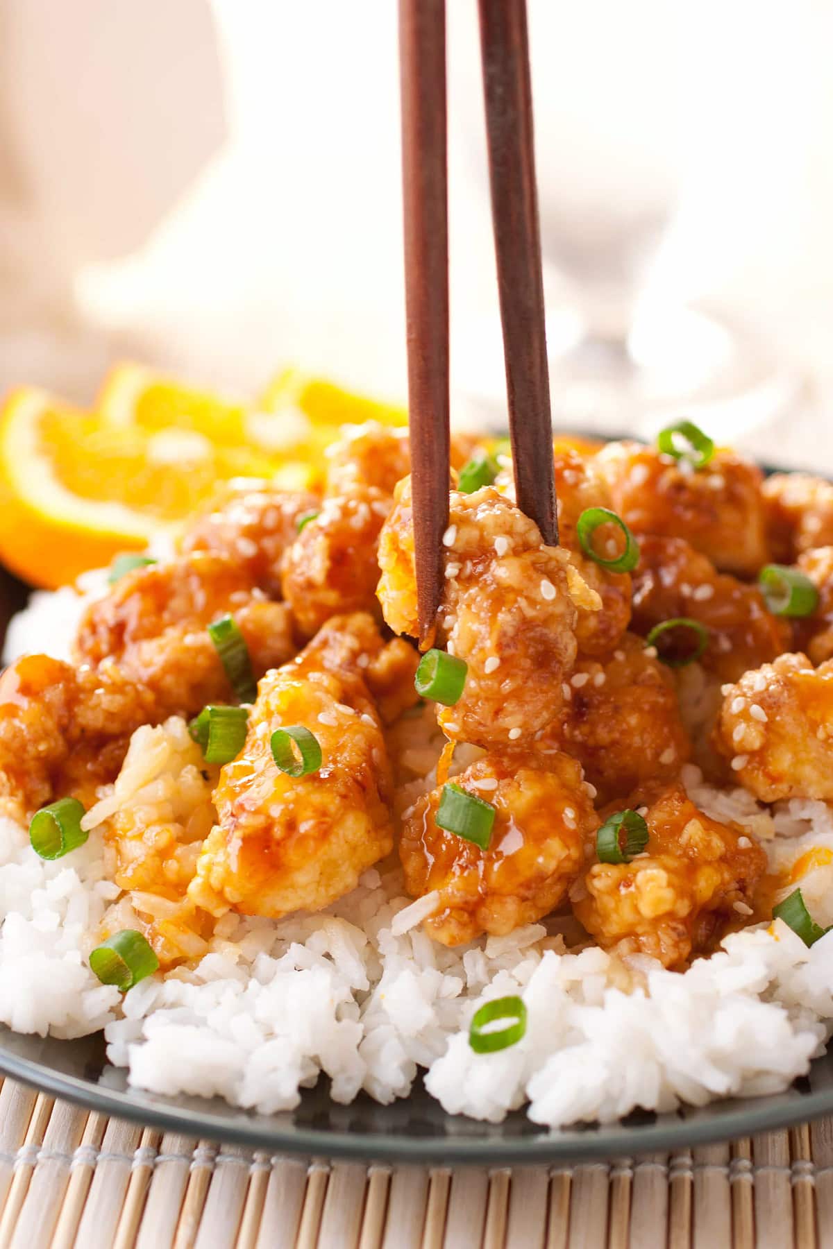 Up close photo of Chinese Orange Chicken with chopsticks grabbing one piece of chicken