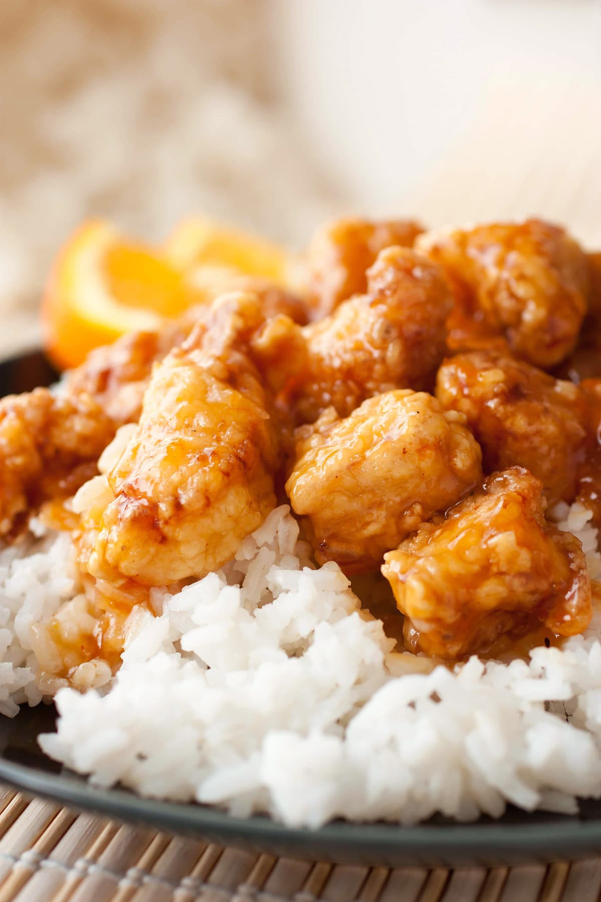 Orange Chicken shown here served over white rice on an individual plate garnished with fresh orange slices