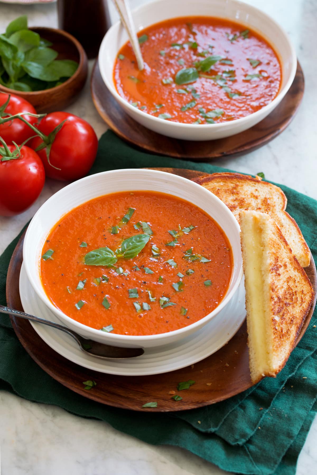 Two servings of tomato basil soup in serving bowls.