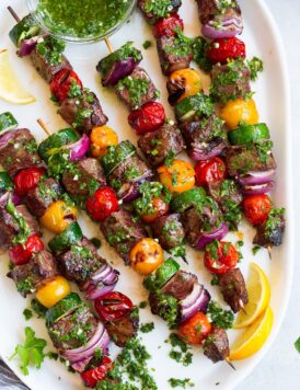steak kebabs on platter with chimichurri