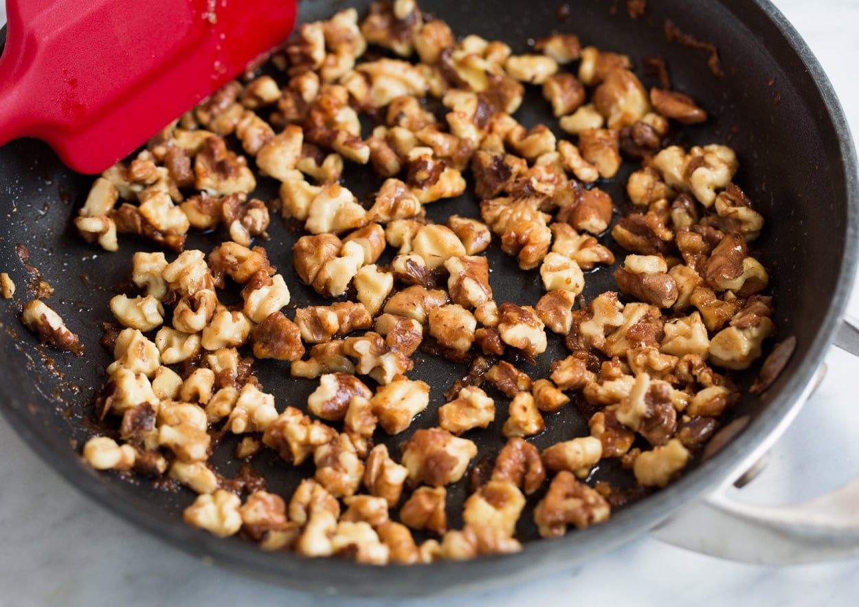 Making candied walnuts in skillet with brown sugar and butter for Pear Salad with