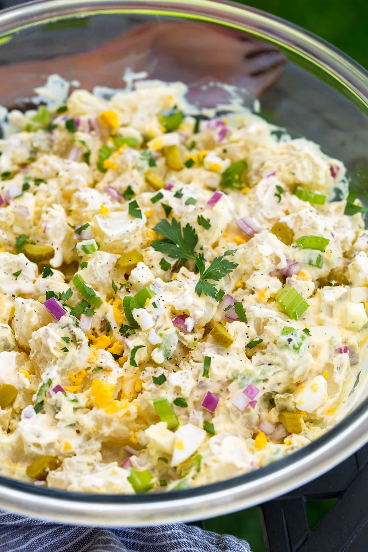 creamy Potato Salad in a glass bowl topped with herbs
