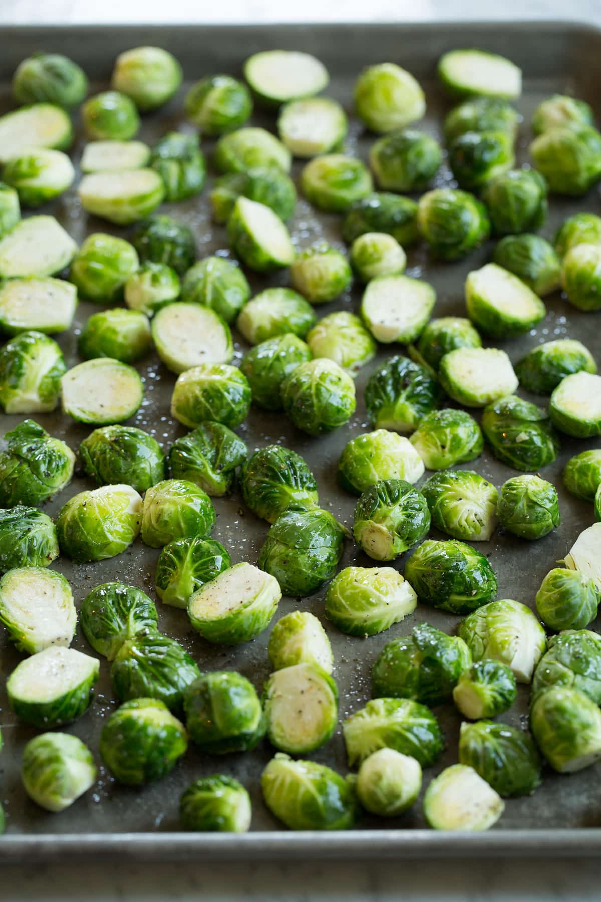 Brussels sprouts on a sheet pan coated with olive oil before roasting