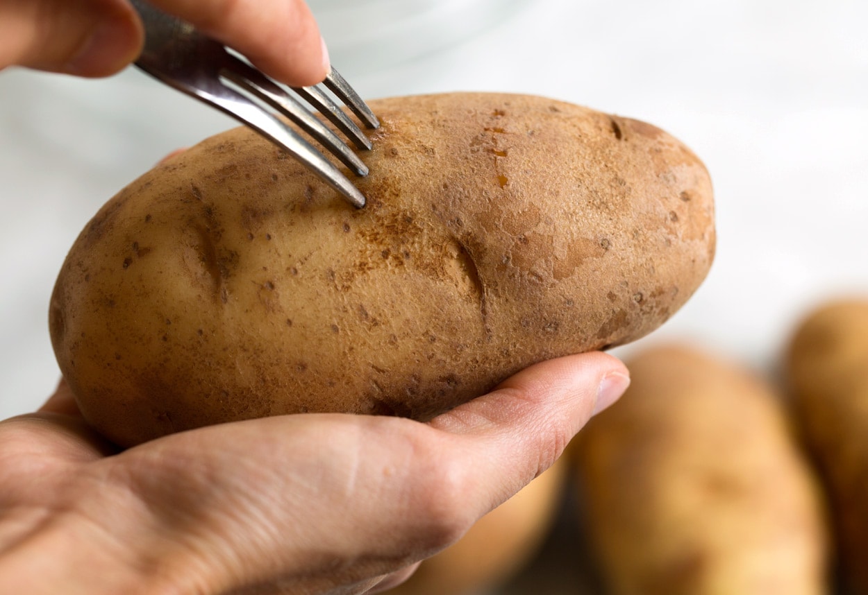 piercing a potato with a fork before baking
