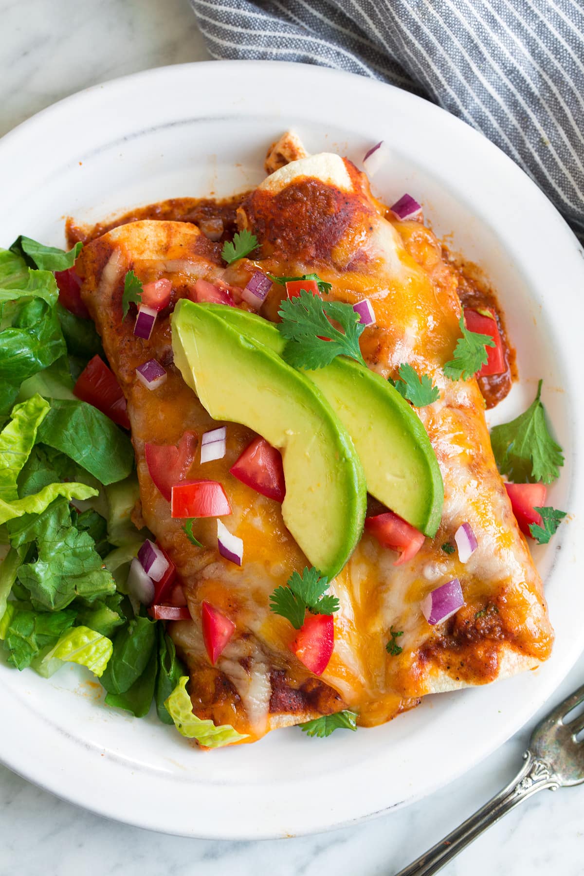 two mexican chicken enchiladas on white plate