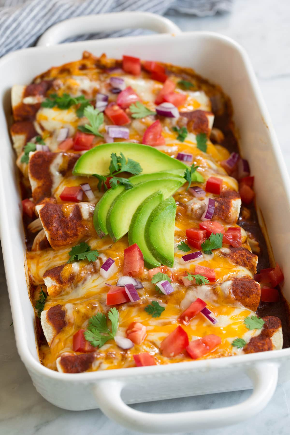 homemade chicken enchiladas with toppings in baking dish