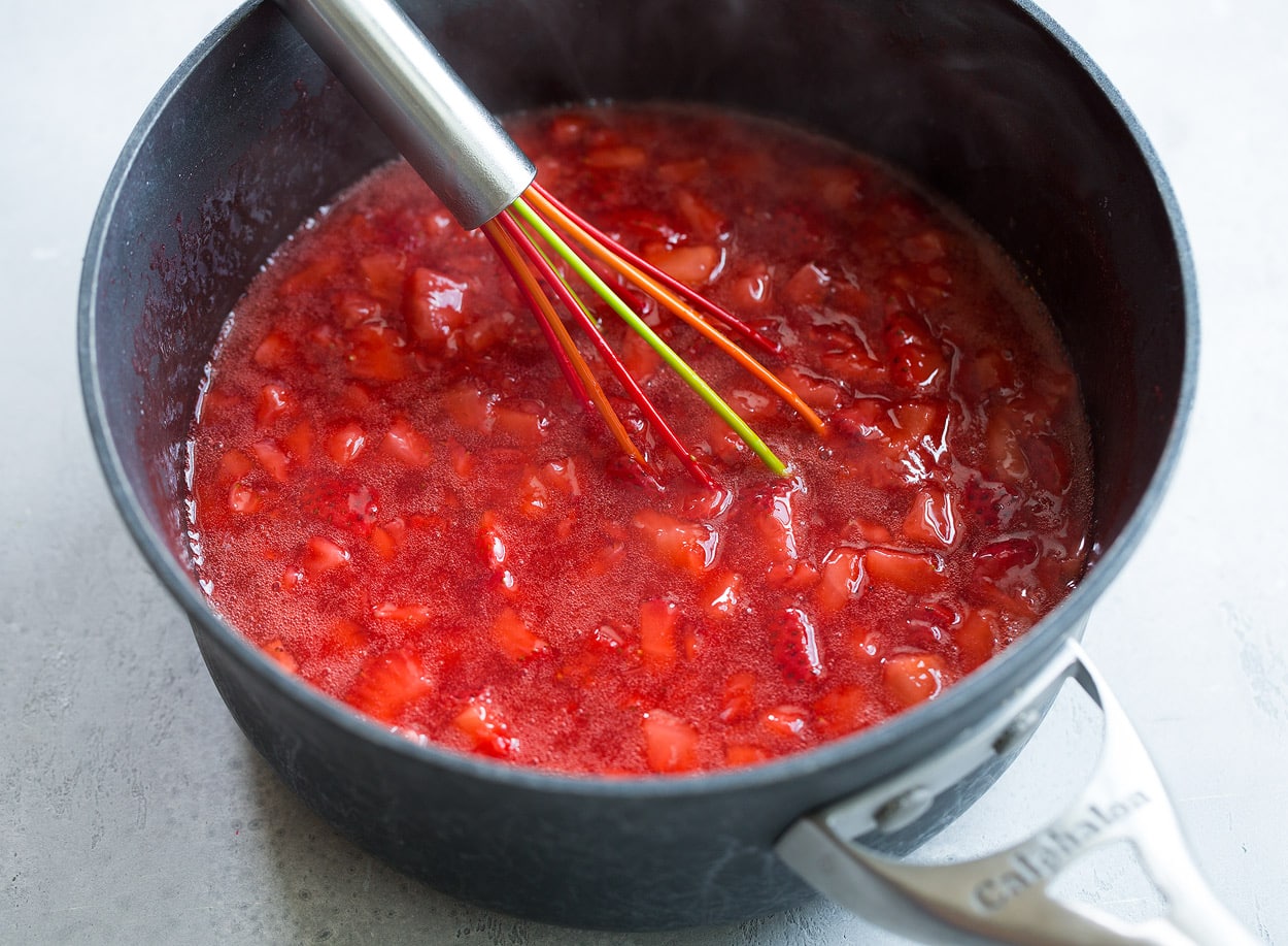 Strawberry Syrup shown here in dark saucepan with whisk