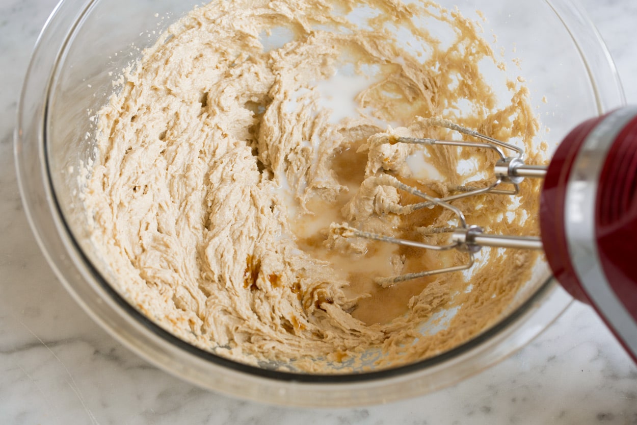 Adding milk and vanilla to sugar butter mixture in mixing bowl for edible cookie dough