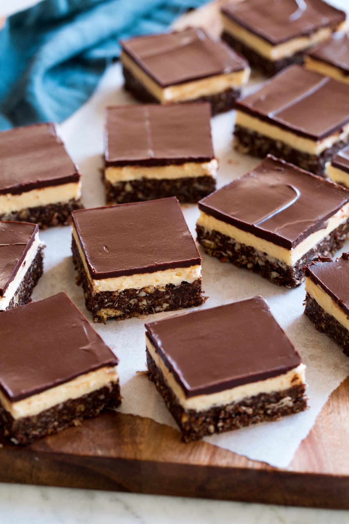 Cut nanaimo bars laying on a piece of parchment paper set over a cutting board.