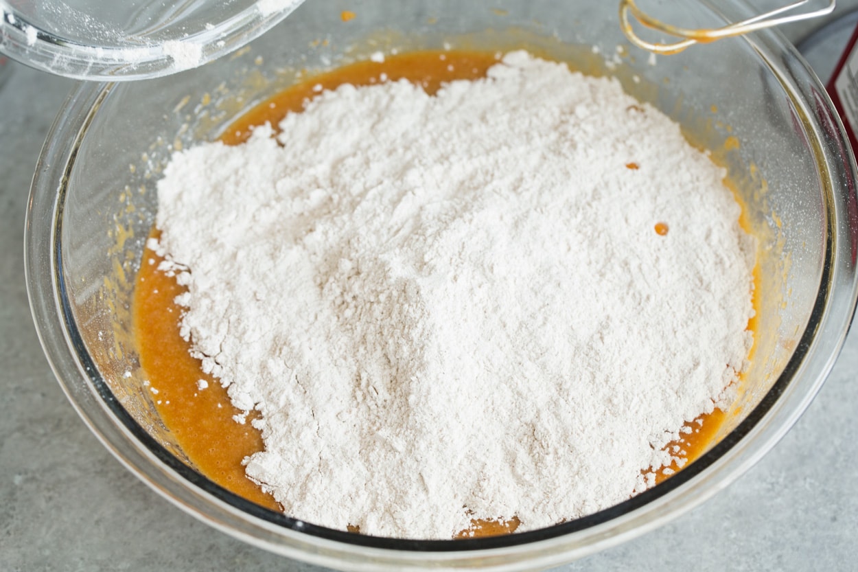 Pumpkin Cake shown here adding dry ingredients to mixture in mixing bowl