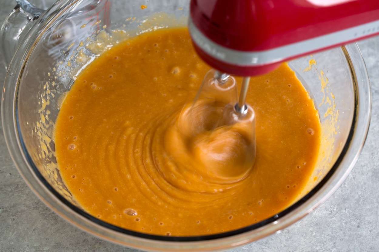 Pumpkin Cake shown here blending mixture in mixing bowl with electric hand mixer