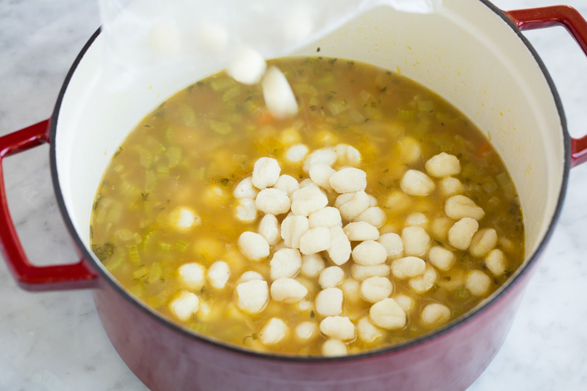 Adding mini gnocchi to soup mixture.
