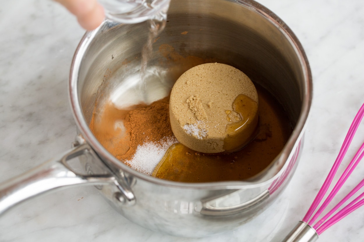 Mixing brown sugar, honey, cinnamon, salt and water in a saucepan to make granola coating.