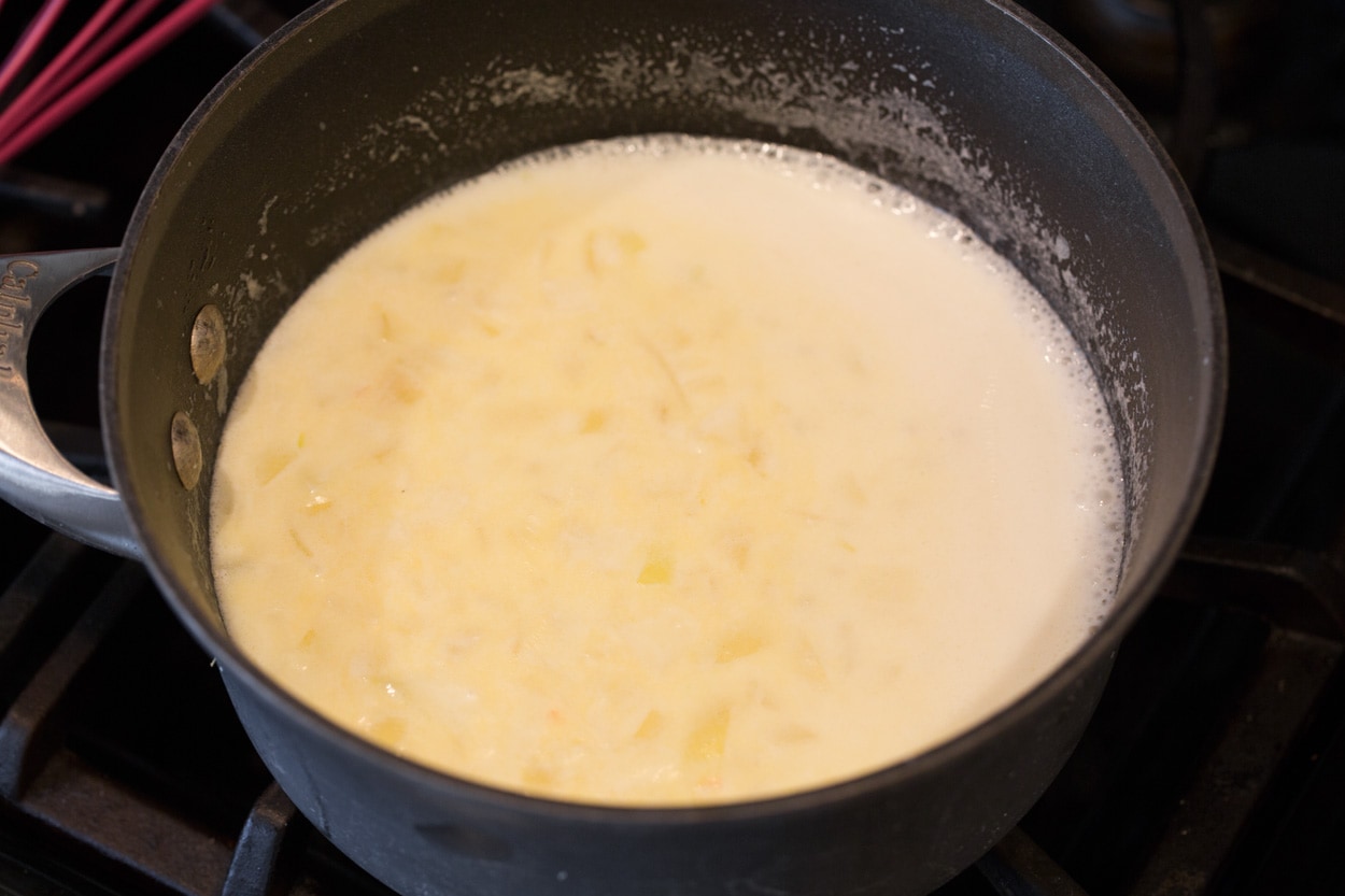 Adding milk to saucepan for scalloped potatoes.