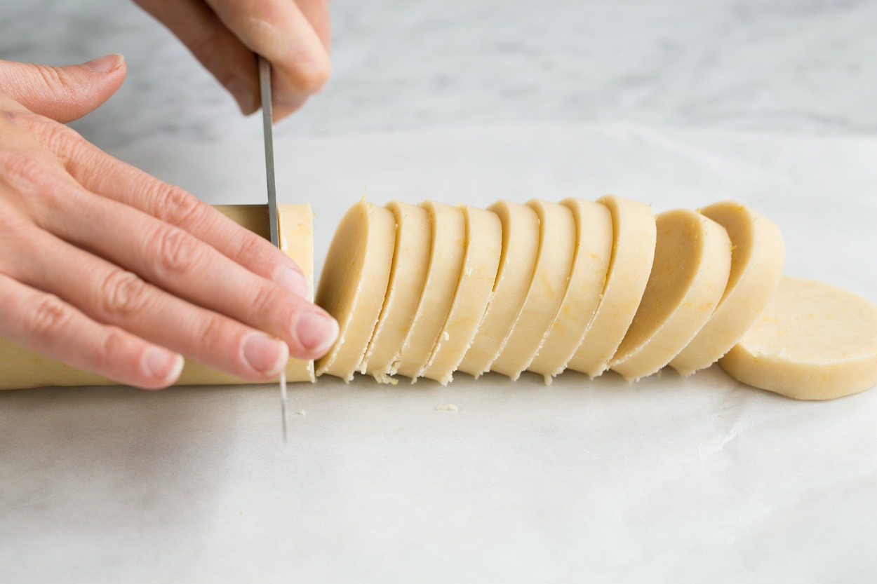 Showing how to make lemon shortbread cookies. Cutting log into slices.