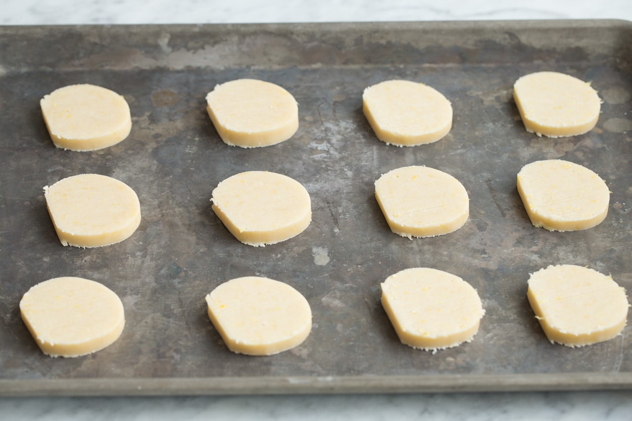 Lemon shortbread cookie dough slices on baking sheet before baking.