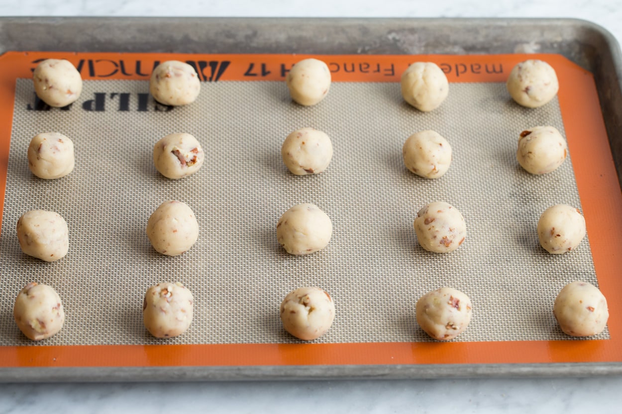 Shaped rounds of Mexican wedding cookie dough balls on baking sheet before baking.