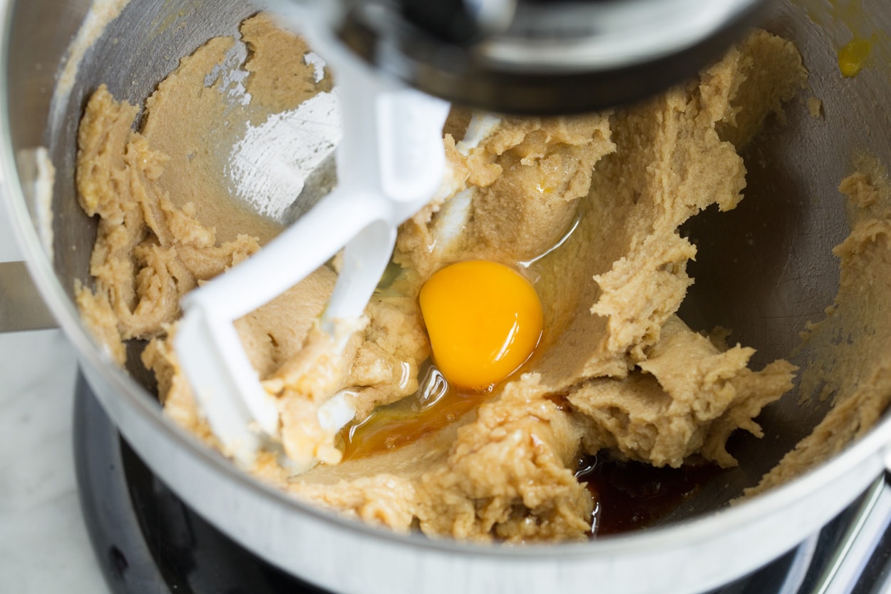 Adding egg and vanilla to mixture in stand mixer.