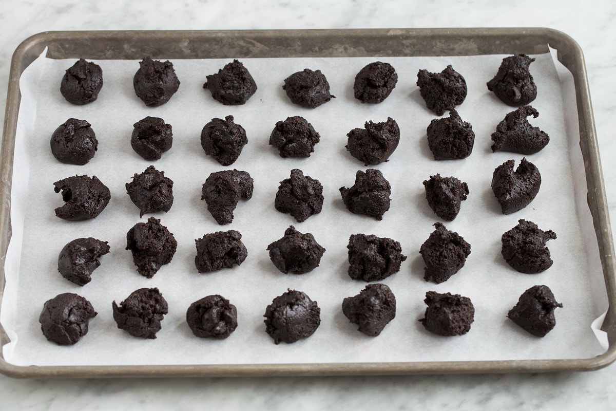 Uneven portions of oreo truffle mixture divided sitting on a baking sheet.
