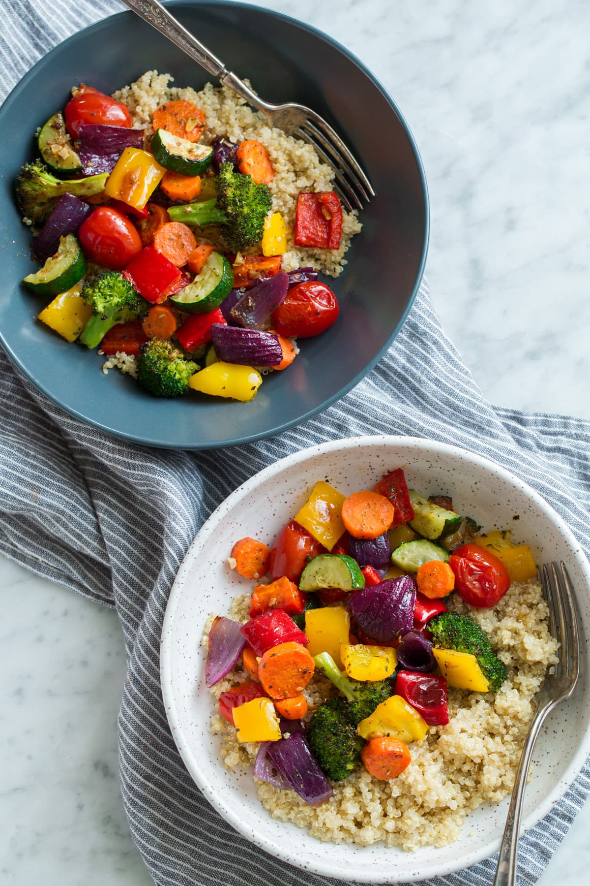 Roasted Vegetables served over quinoa with lemon in two serving bowls.