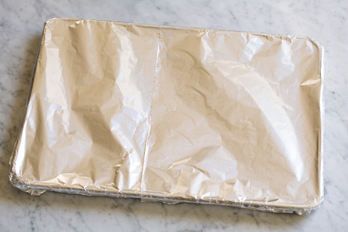 Covering baking sheet with aluminum foil.