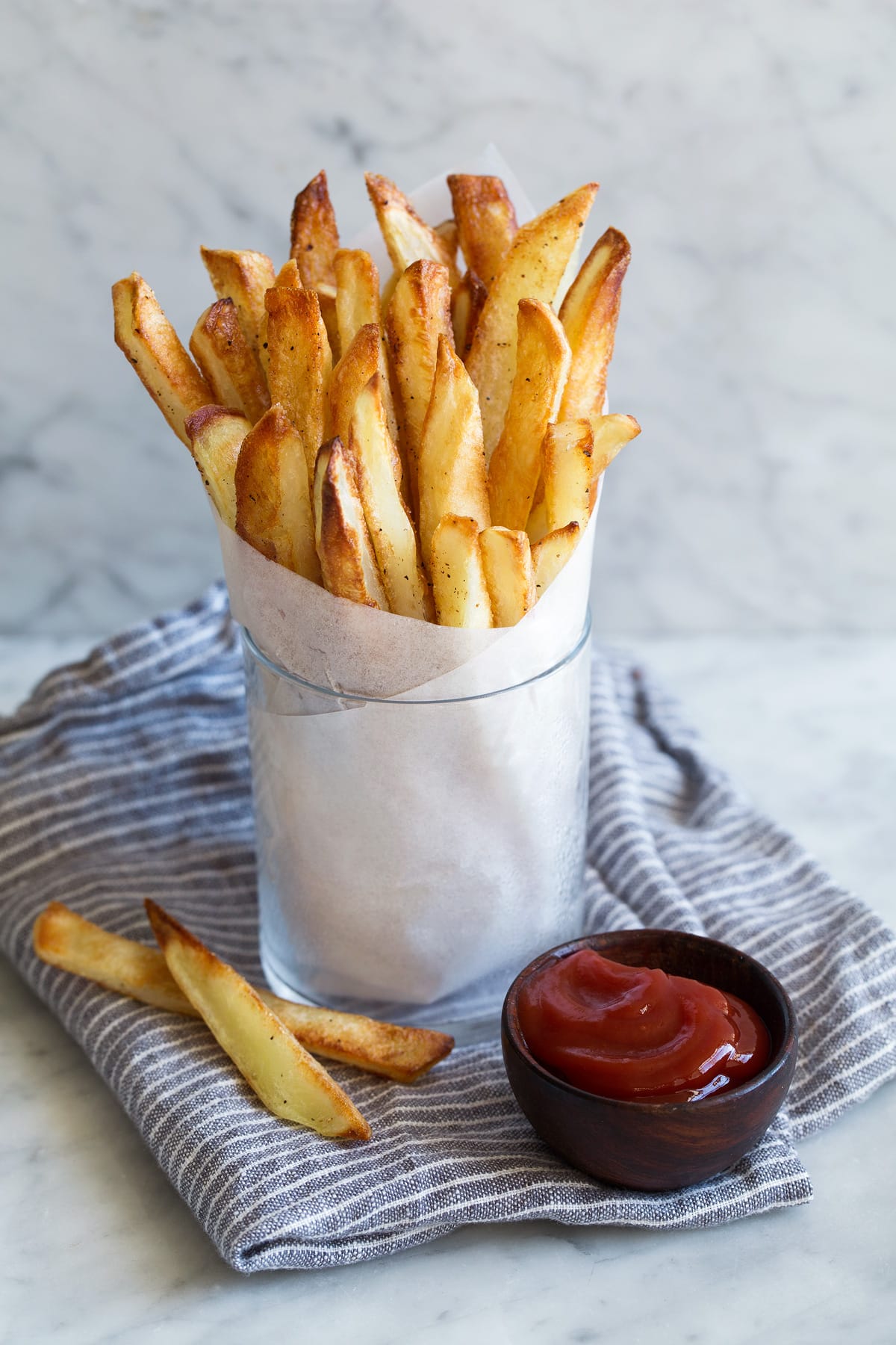 Cup full of french fries in parchment paper with a side of ketchup.