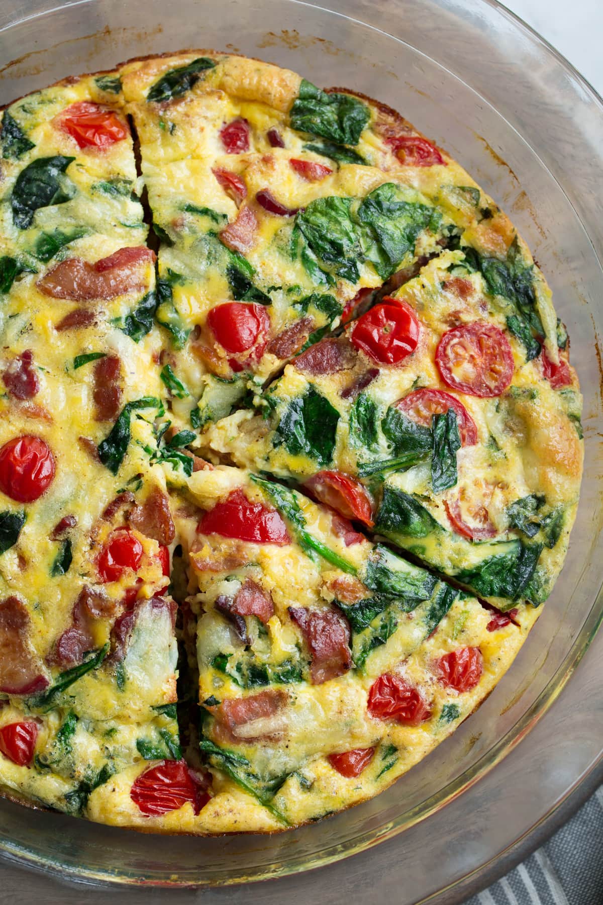Frittata in a glass pie plate set over a wooden surface.