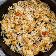 Overhead image of shredded hash browns in black cast iron skillet.