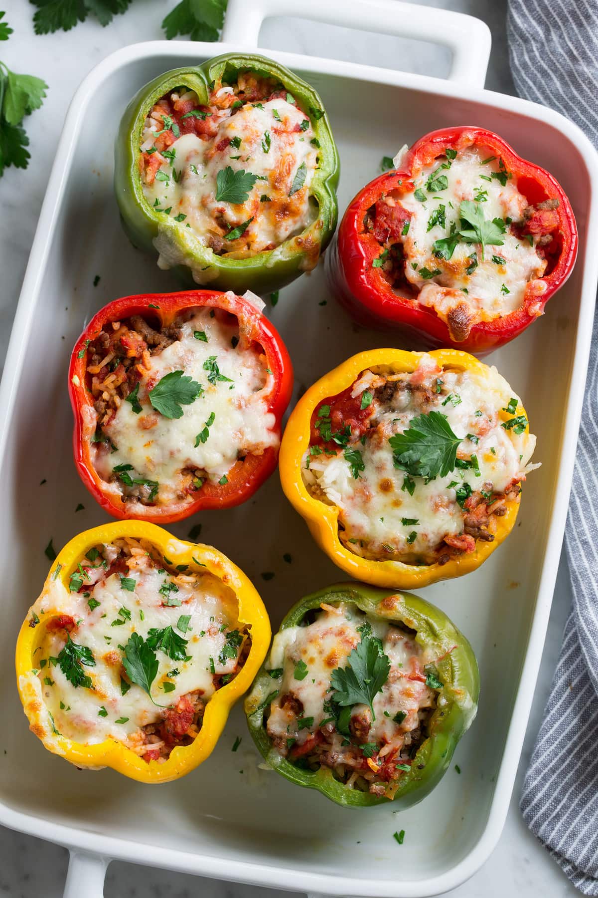 Overhead image of six stuffed peppers in a white baking dish.