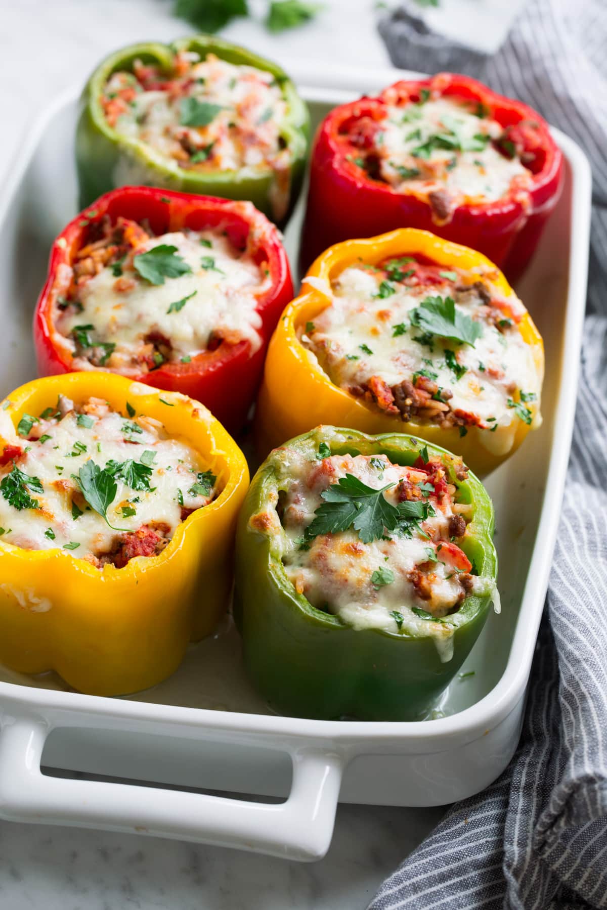 Multi-color stuffed peppers in a white baking dish.