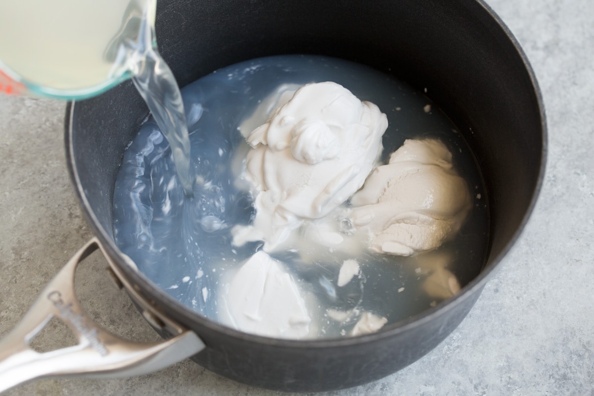 Adding water and coconut milk to a medium saucepan.