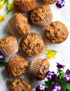 Overhead image of morning glory muffins on a marble surface decorated with spring flowers.