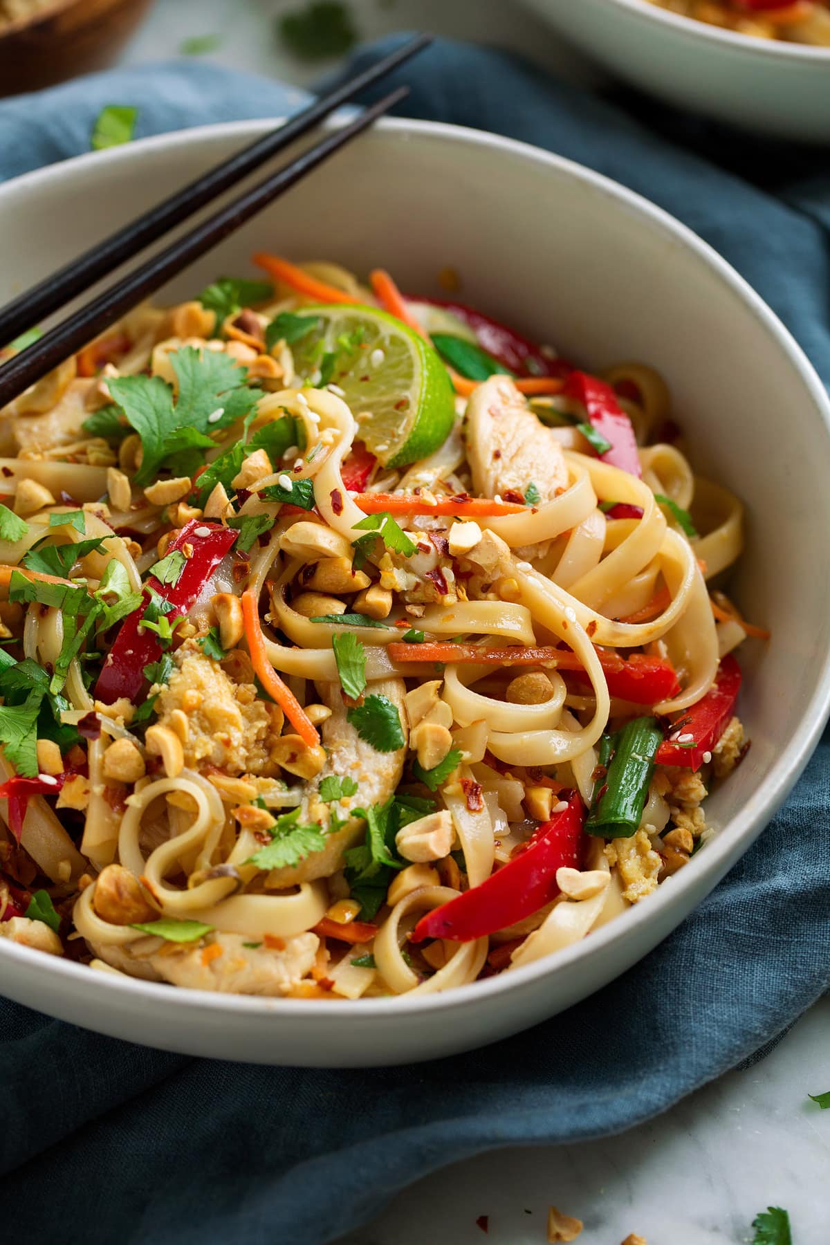 Close up image of Pad Thai showing rice noodles, vegetables, chicken, peanuts and cilantro.